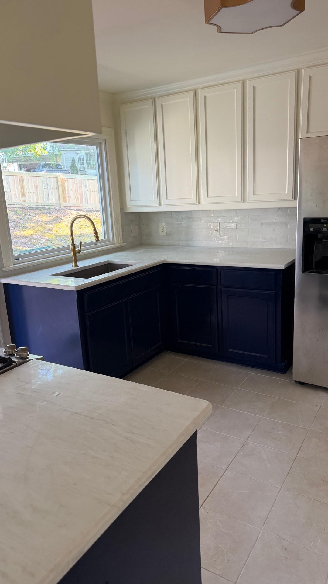 Refinished white upper cabinets and deep navy lower cabinets in a kitchen